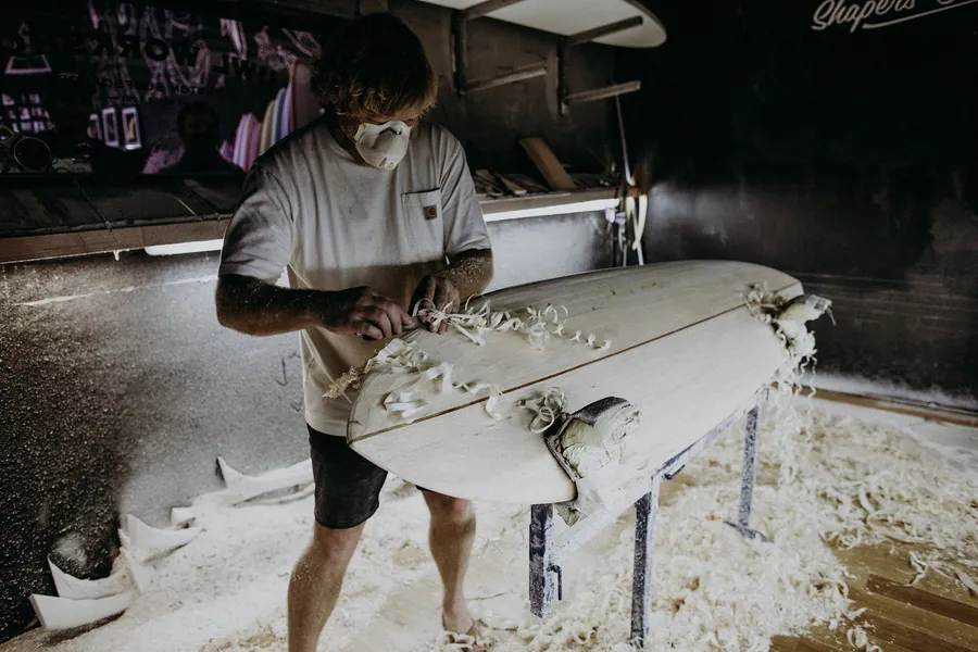 Joshua Martin hand-shaping a longboard in his workshop