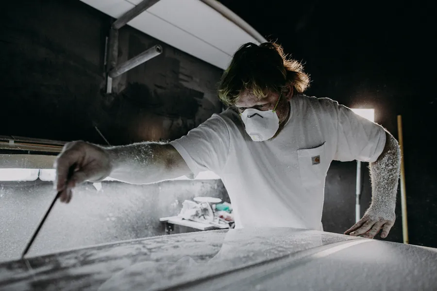 Joshua Martin checking a surfboard line while shaping