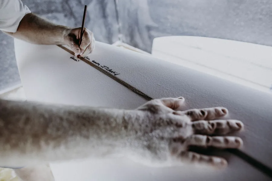 Joshua Martin signing a hand-shaped surfboard