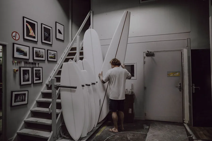 Joshua Martin moving several longboards inside the workshop